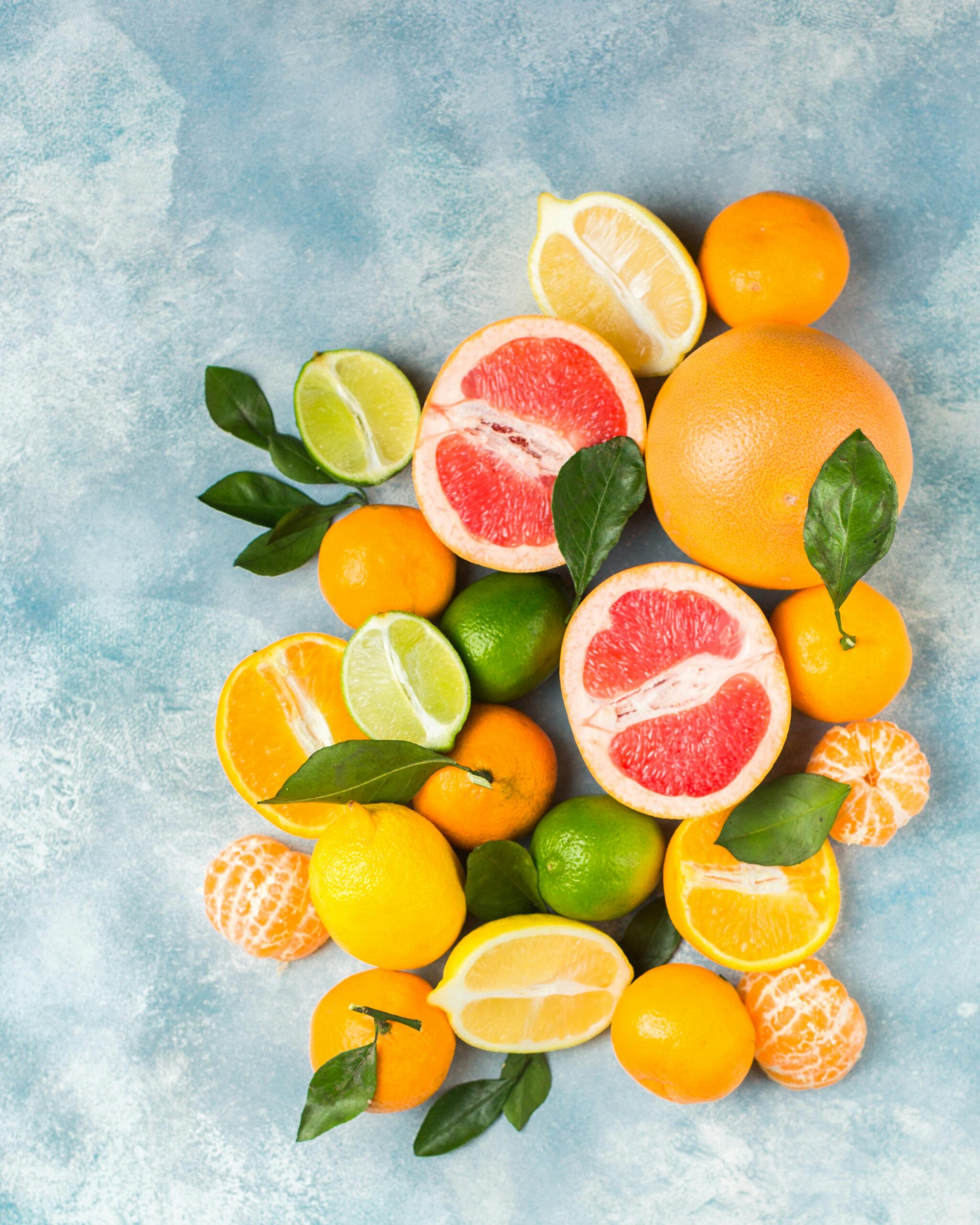 Colorful assortment of fresh citrus fruits including grapefruits and lemons on a vibrant blue background.