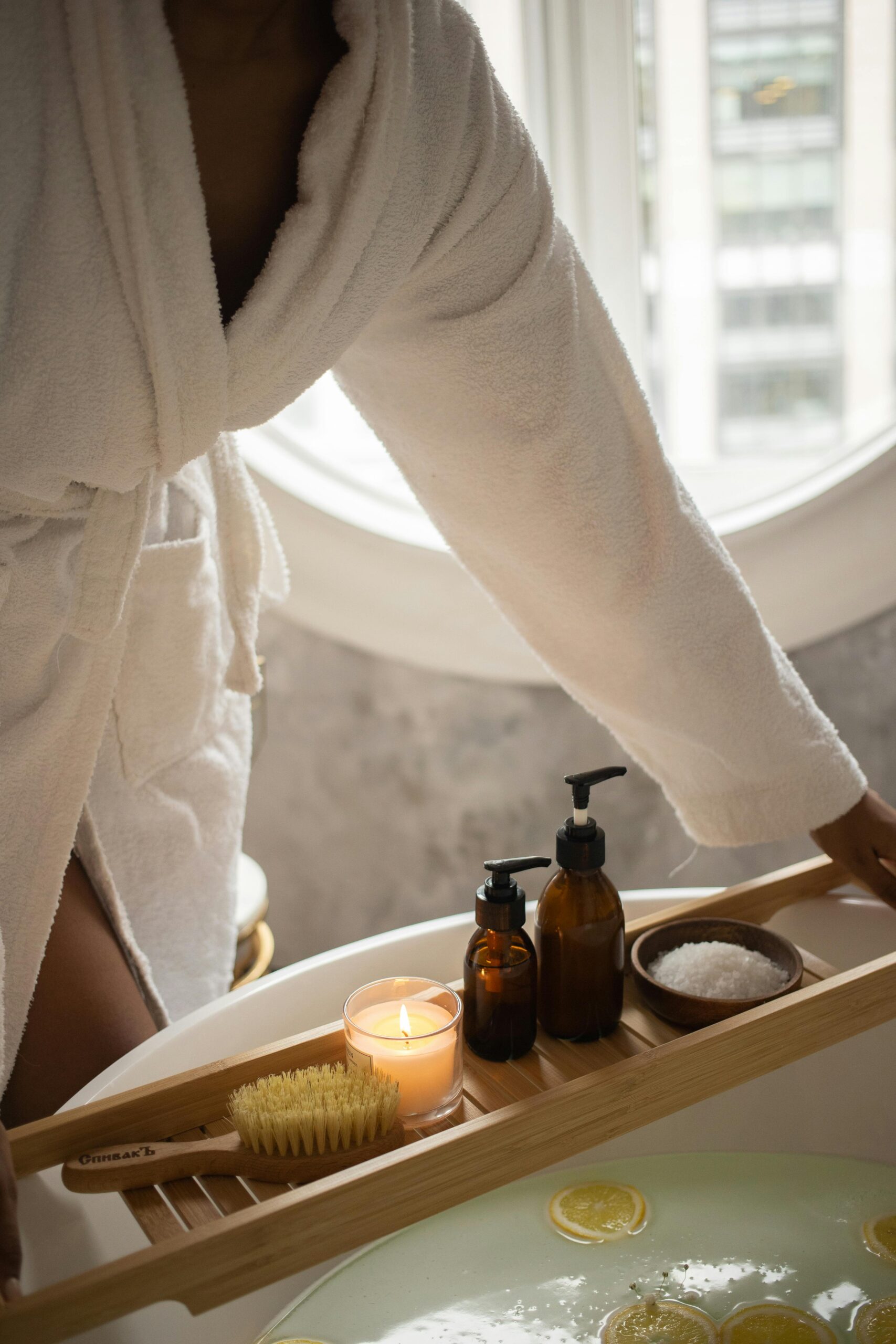 A tranquil bathroom scene featuring spa essentials and a woman in a bathrobe by the tub.