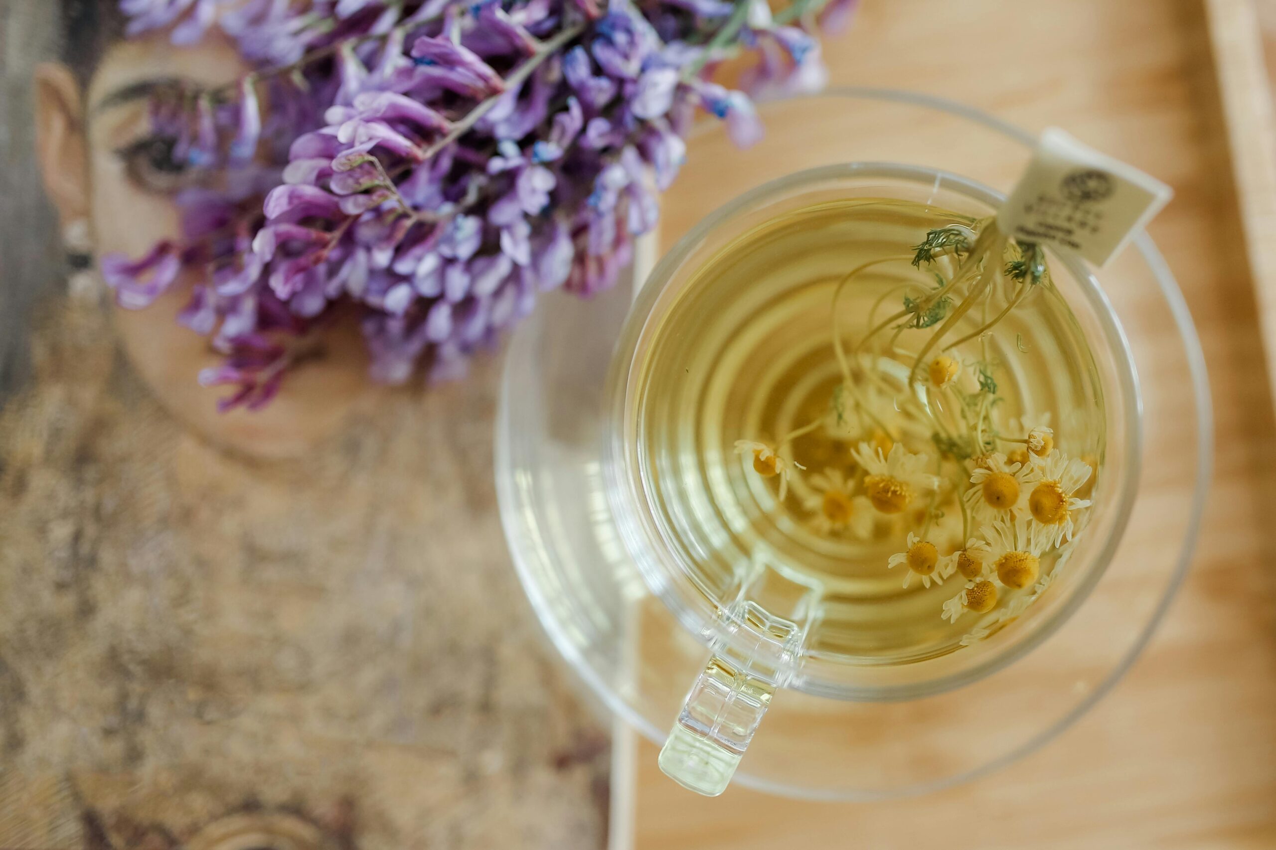 Top view of chamomile tea with lavender flowers on a tray, offering a soothing herbal experience.