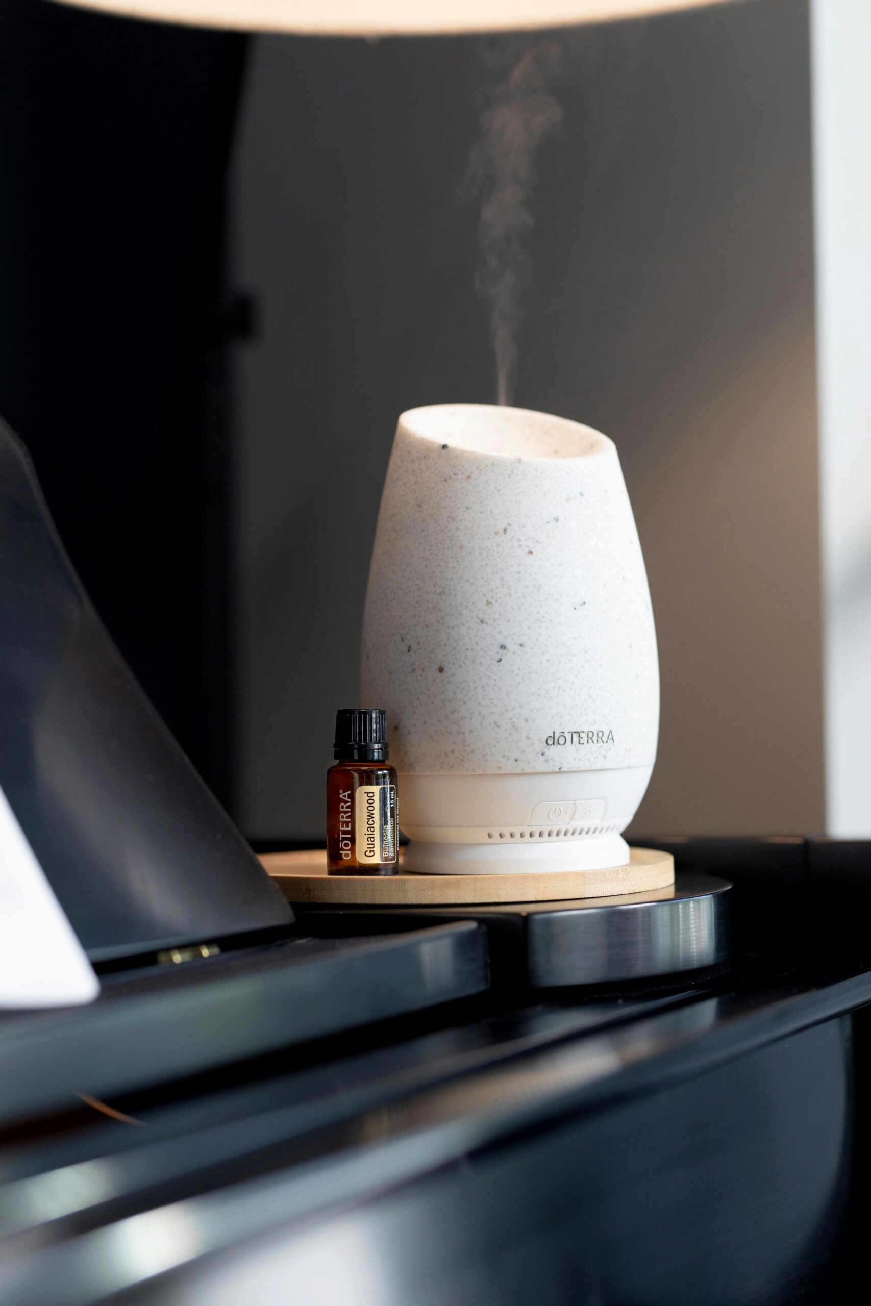 Stylish aromatherapy diffuser emits calming steam indoors next to essential oil vial.