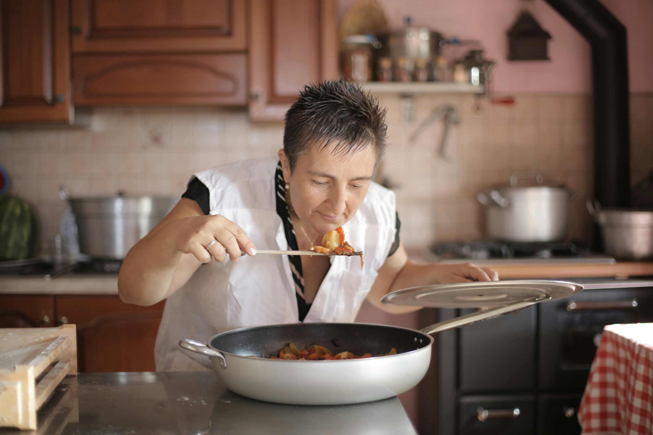 A woman savoring the aroma of a freshly cooked dish in a cozy kitchen setting.
