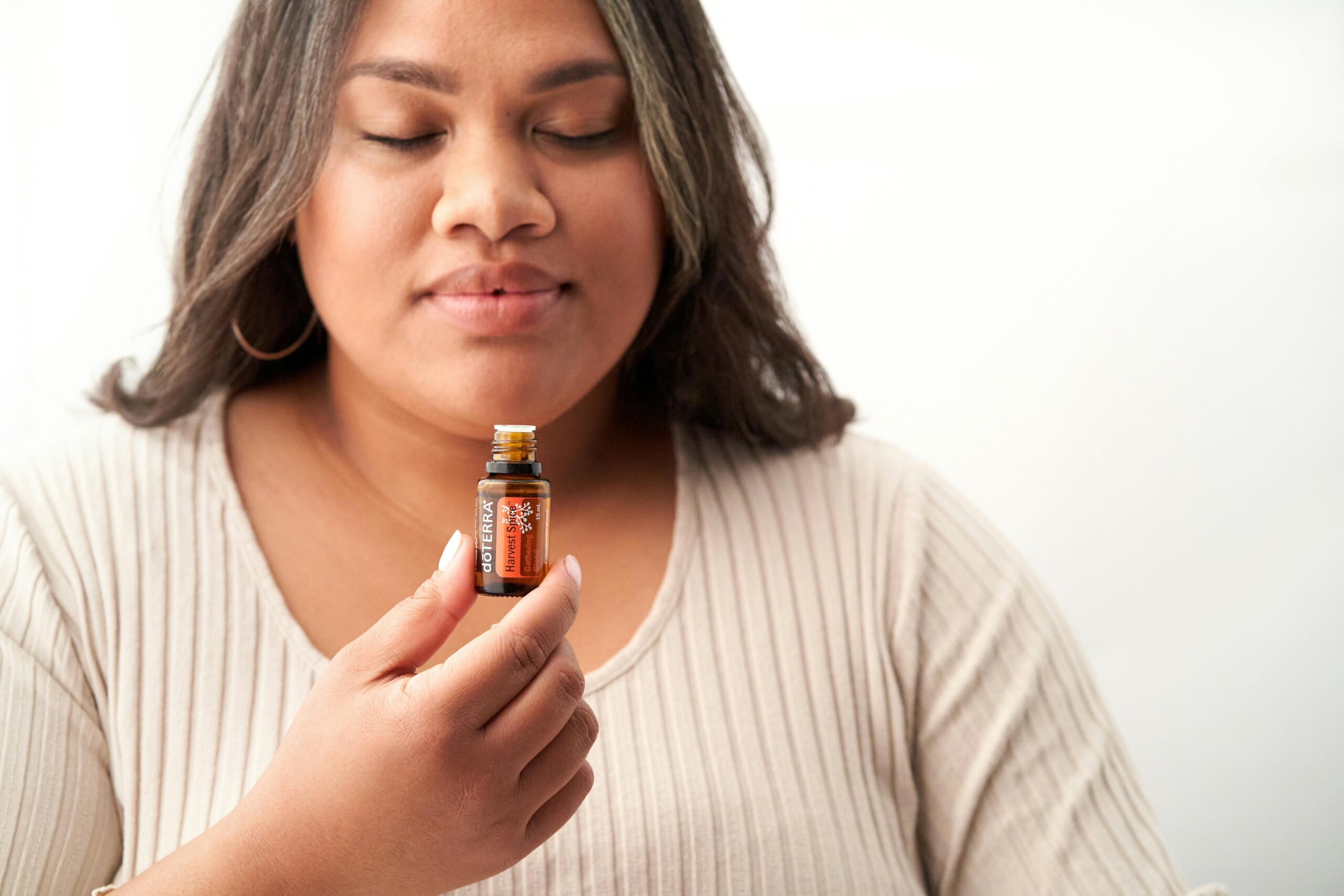 Close-up of a woman savoring the scent of essential oil on a white background.