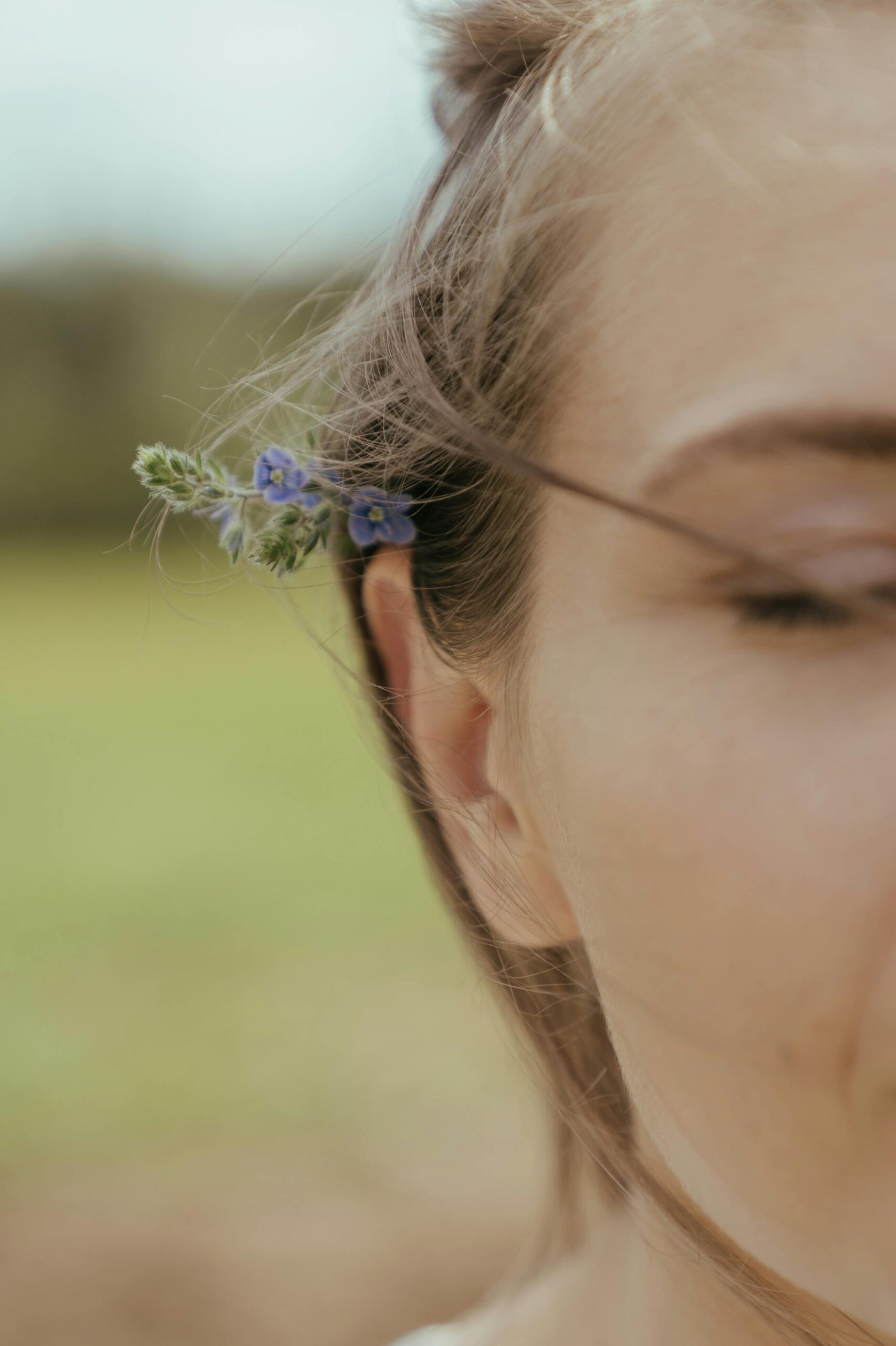 A serene portrait capturing the natural beauty with flowers tucked behind the ear.