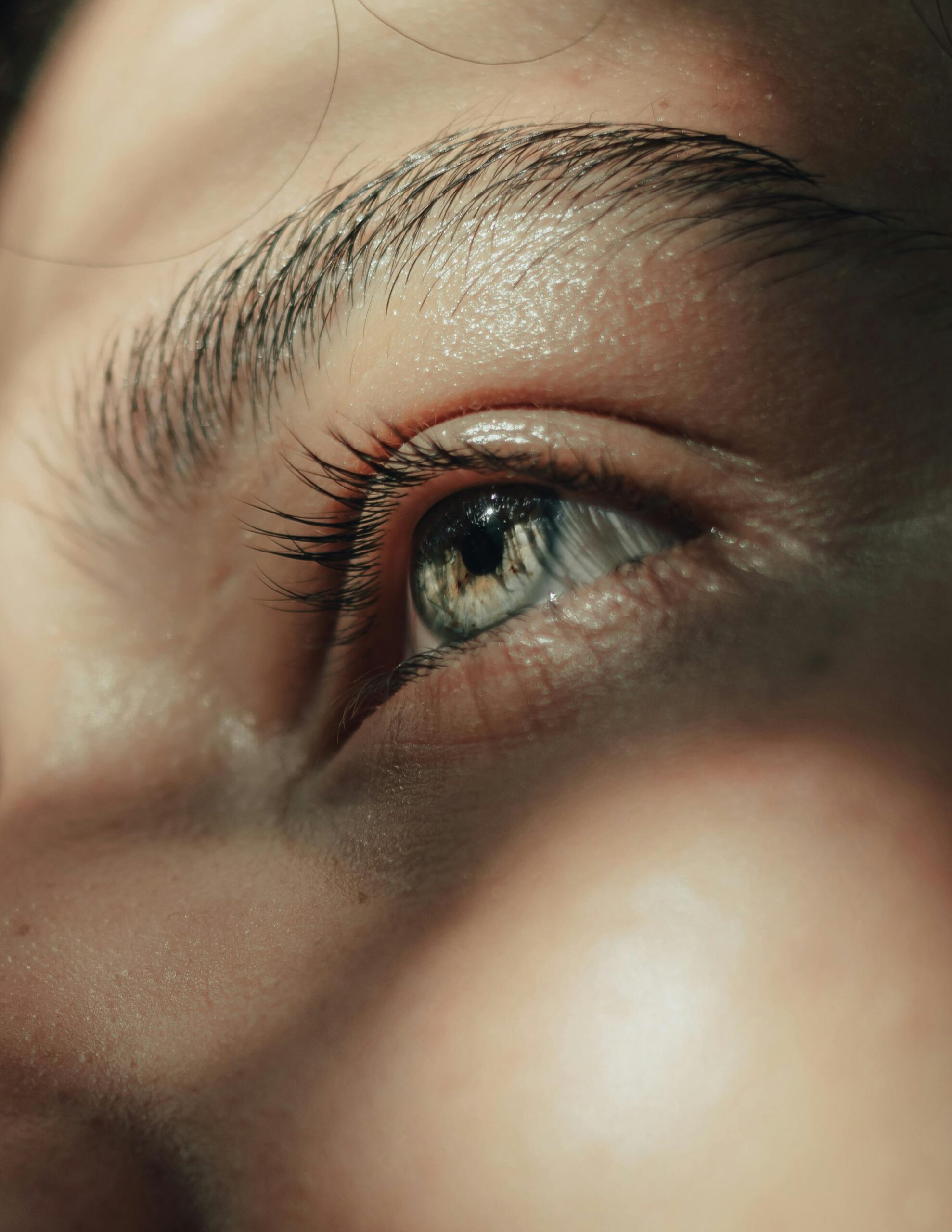 Artistic close-up capture of a blue eye highlighting intricate details and natural sunlight reflections.