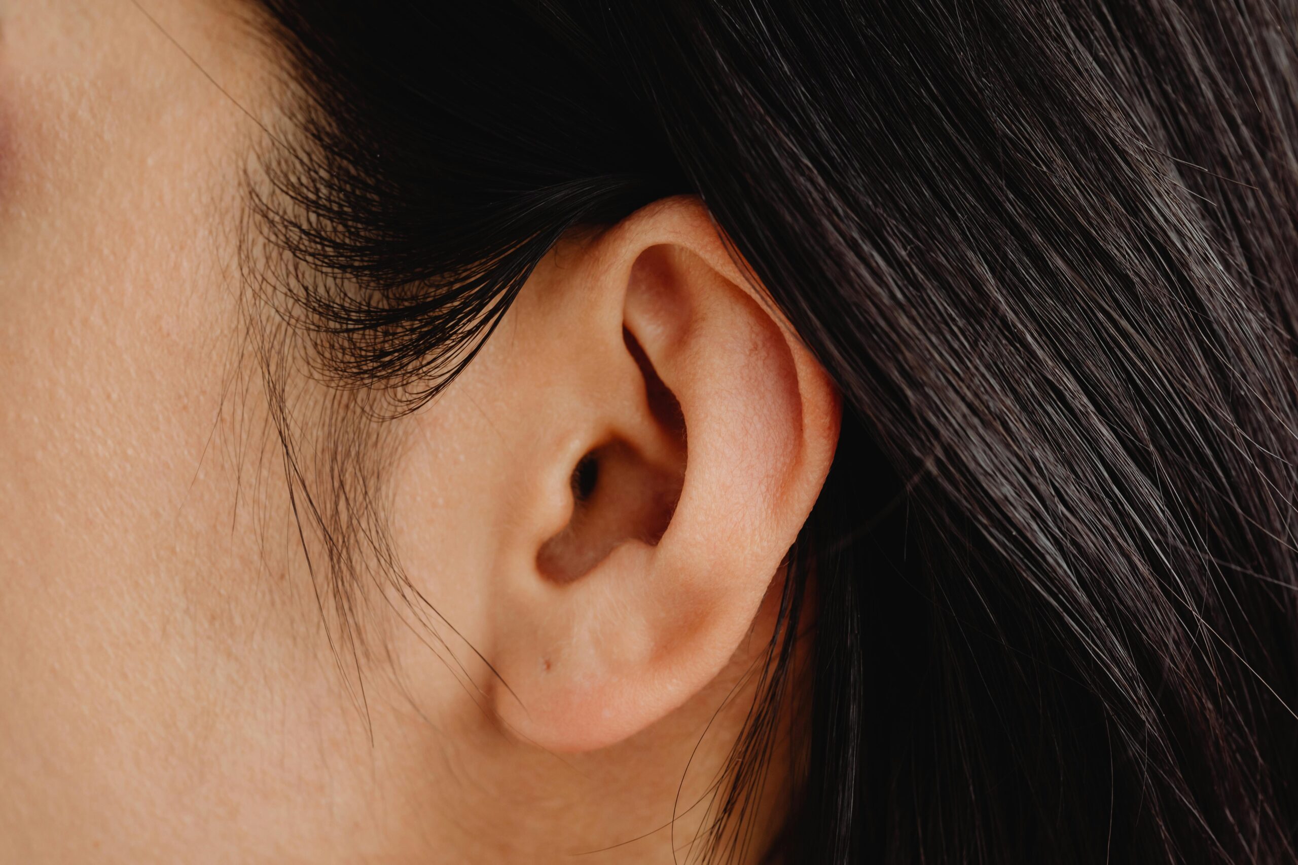 Detailed close-up photo showcasing a human ear with dark hair.